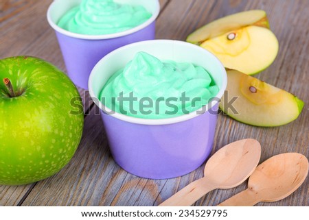 Serving of frozen homemade creamy ice yoghurt  with fresh green apples and wooden spoon. Green healthy bio organic and vegan dessert.
