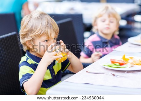 Two little kid boys having healthy breakfast in hotel restaurant or city cafe. Selective focus.