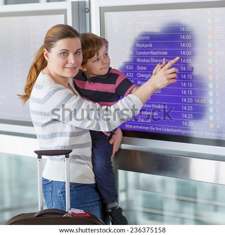 Happy family of two: Mother and little son at the international airport, looking on flight board at terminal, going on vacation.