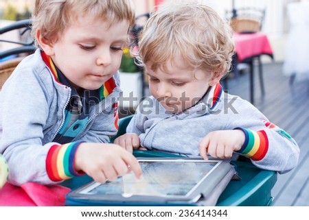 Two little sibling boys having fun together with tablet pc