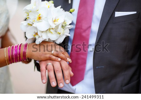 Beautiful indian bride and caucasian groom, after wedding ceremony. hands of man and woman with rings and traditional indian jewelry