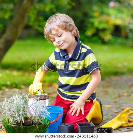 Adorable little blond boy of 3 or 4 years gardening and planting flowers in home\'s garden or farm, on warm sunny day. Outdoors. Environment concept.