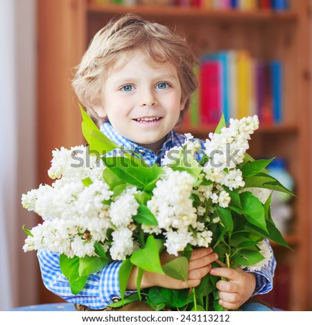 Adorable smiling little toddler boy with blooming white lilac flowers, indoor. Mother\'s day, father\'s day or valentine\'s day concept. Birthday card.