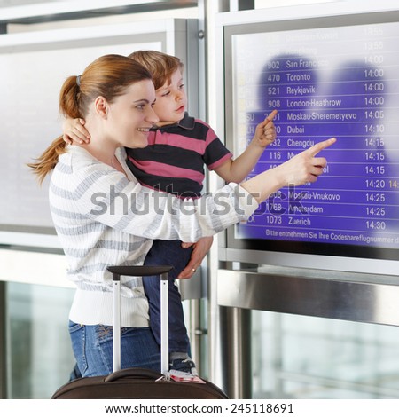 Happy family of two: Mother and little son at the international airport, looking on flight board at terminal, going on vacation.