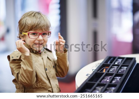Cute little kid boy at optician store during choosing his new glasses.