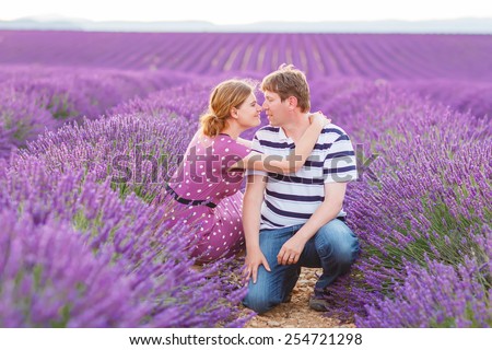 Romantic couple in love in lavender fields, having vacations in Provence, France. Beautiful young man and woman hugging at sunset.