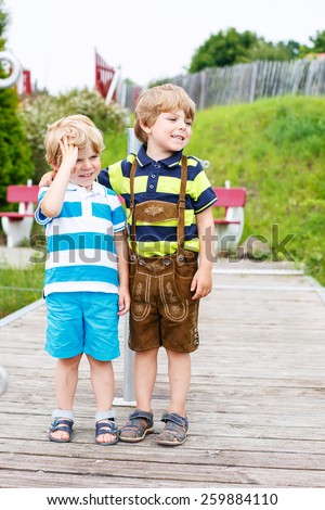 Two happy adorable little sibling boys hugging. Boys in shorts on warm summer day, having fun on family vacations, outdoors.
