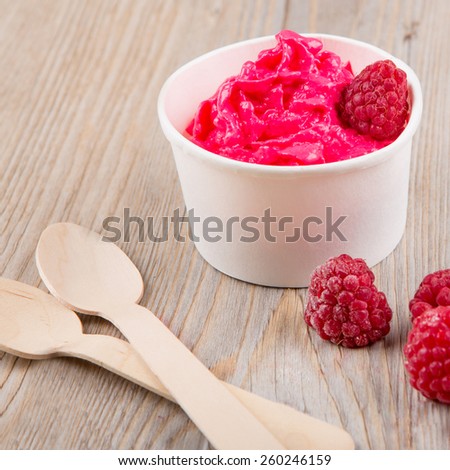 Serving of frozen creamy ice yoghurt  with whole fresh raspberries and wooden spoon, Healthy bio organic vegan dessert.
