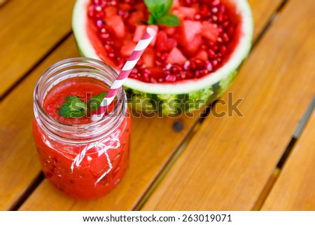 Watermelon and pomegranate smoothie as healthy summer vegan drink. With hollowed watermelon and pomegranate