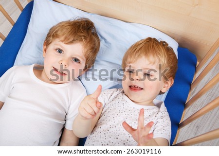 Family of two little boys: Twins having fun in bed at home, indoors.