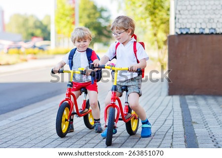Two little siblings children having fun on bikes in city on vacations, outdoors. Brother kid boys riding with bicycles.