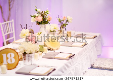 Elegant table set in green and white for wedding or event party. Flower arrangements, candles, china and porcelain tableware and napkis. Wedding details.