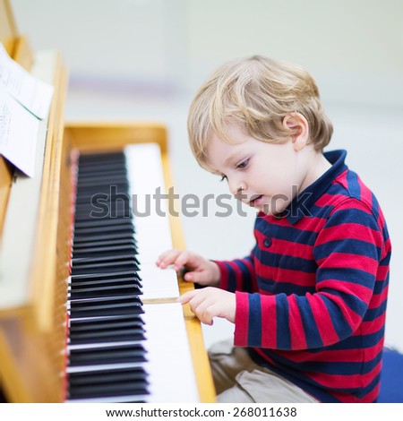 Two years old funny positive toddler child playing piano. Early music education for little kids. child at school, learning music instrument.