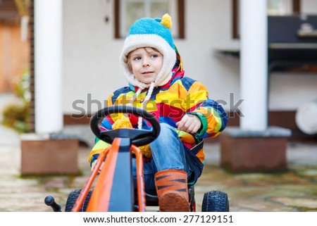 Active preschool kid boy having fun with toy race cars, outdoors. Child driving car. Outdoor games for children concept.