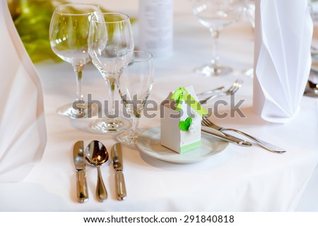 Table set in green and white for wedding or event party. Luxury decoration for celebration, with give away for guests
