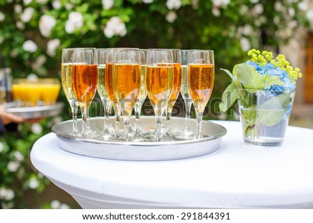 Dish with champagne and wine glasses. On outdoor wedding reception in summer.