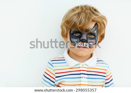 Beautiful little kid boy with face painted with animal or cat, on a birthday party. happy child having fun.