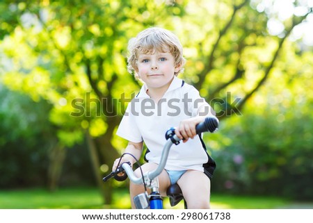 Happy cute blond kid boy having fun his first bike  on sunny summer day, outdoors. Happy child making sports. Active leisure for children.