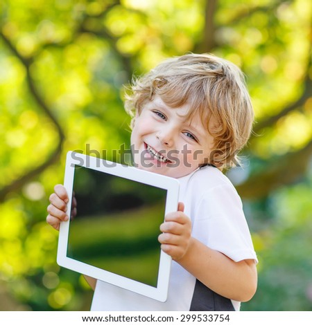 Adorable happy little child playing with gadget, outdoors. Preschool boy learning with modern technology. Education and addiction concept.