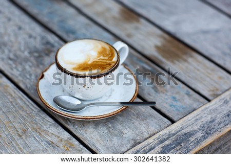 Cup of coffee on a wooden table, in an outdoor cafe
