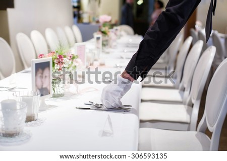 Man covering table with cutlery. Table set in soft pink and white for wedding or event party. Luxury set for celebration, with give away for guests