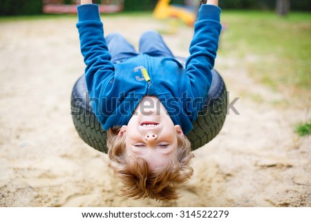 Funny happy preschool kid boy having fun chain swing on outdoor playground. child swinging on warm sunny summer day. Active leisure with kids. Family, lifestyle, summer concept