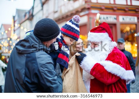 Little toddler boy with father on Christmas market. Funny happy kid taking gift from bag of Santa Claus. holidays, christmas, childhood and people concept