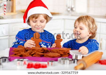 Two little kid boys baking gingerbread cookies. Happy siblings, children in blue xmas pullovers. Kitchen decorated for Christmas. Family, holiday, kids lifestyle conceplt.
