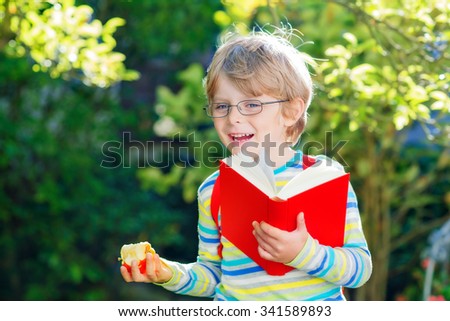 Happy little kid boy with glasses, books, apple and backpack on his first day to school or nursery. Child outdoors on warm sunny day, Back to school concept