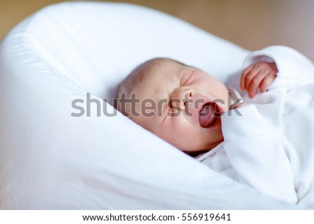 Cute adorable newborn baby crying in white bed. New born child, little girl laying in bed. Family, new life, childhood, beginning concept.