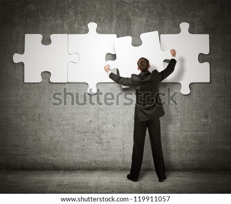 Businessman making a puzzle on the wall