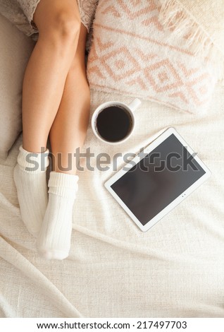 Soft photo of woman on the bed with tablet and cup of coffee, top view point