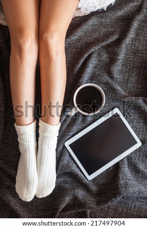Soft photo of woman on the bed with tablet and cup of coffee, top view point