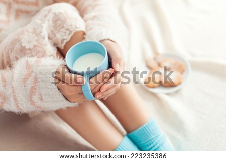 Soft photo of woman on the bed with cup of milk in hands, top view point
