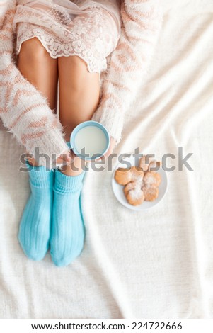 Soft photo of woman on the bed with cup of milk in hands, top view point. Cozy, comfy, soft