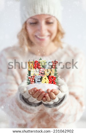 Young woman in mittens holding snow in her hands with colorful text Happy new year. Unusual christmas concept