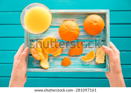 Woman holds a vintage tray with mandarins and fresh juice in her hands. Top view