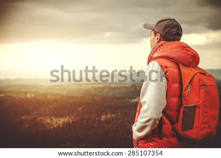 Man with backpack is standing on a mountain.