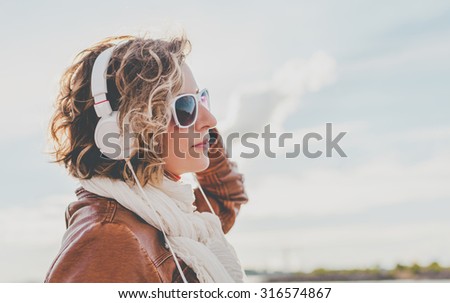 Young woman with headphones at against the sky