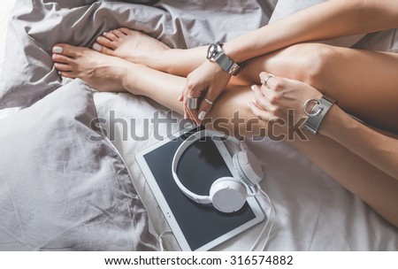 Soft photo of woman on the bed with tablet and headphones, top view point