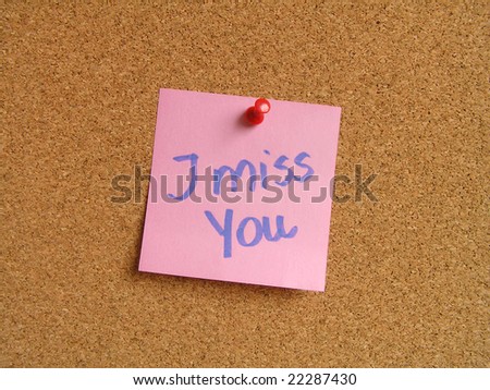 Pink small sticky note on an office cork bulletin board. I miss you.