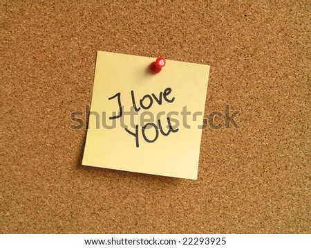 Yellow small sticky note on an office cork bulletin board. I love you confession.
