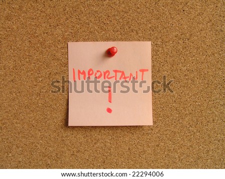 Orange small sticky note on an office cork bulletin board. Important message.