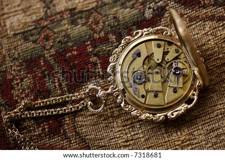antique ladies gold watch with back open, exposing the clockwork.