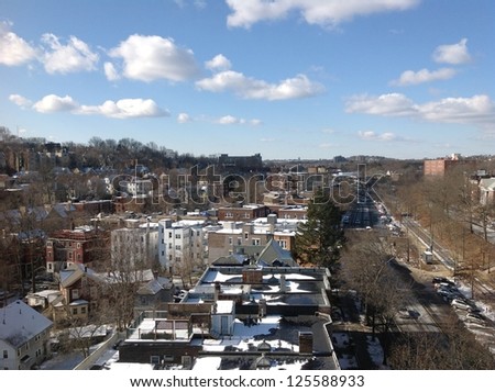 Busy street with houses and buildings under blue sky, suburban Boston