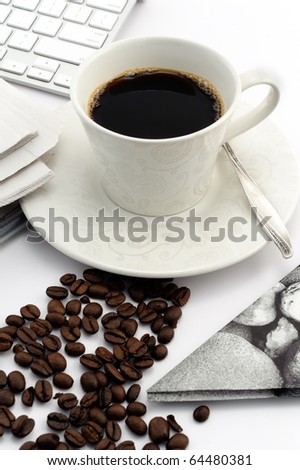 Espresso coffee in white vintage cup with coffee beans, silver teaspoon, napkin, keyboard and newspaper