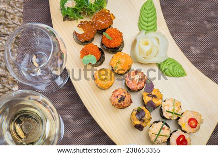 Roll set on wooden plate served at the restaurant, with wine and decor