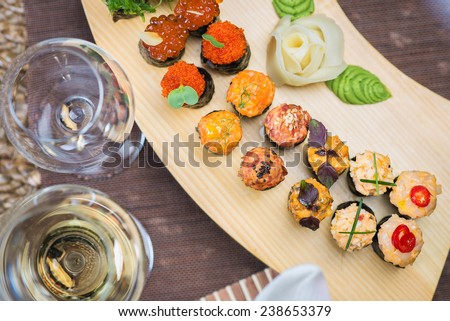 Roll set on wooden plate served at the restaurant, with wine and decor