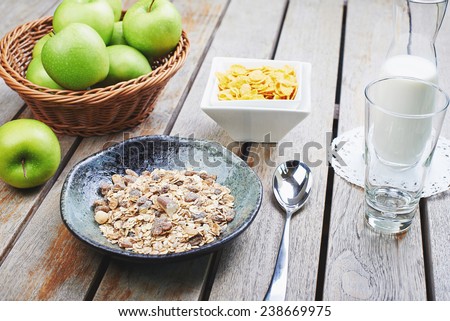 Oat cereal with fresh milk and green apples on a wooden table