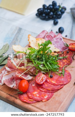 Traditional italian antipasto with prosciutto and different sorts sausage on a wooden table
